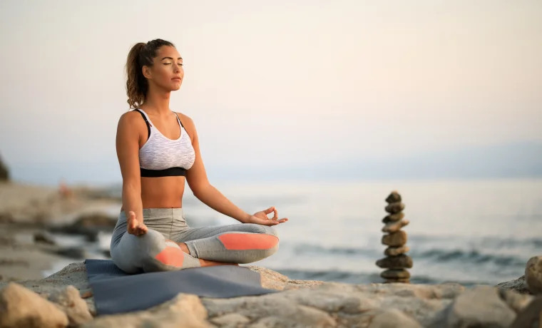 Woman meditating by the sea in seated yoga posture