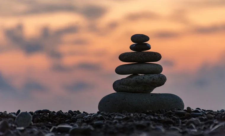 Balanced pebbles and stones stacked on pebble beach at sunset