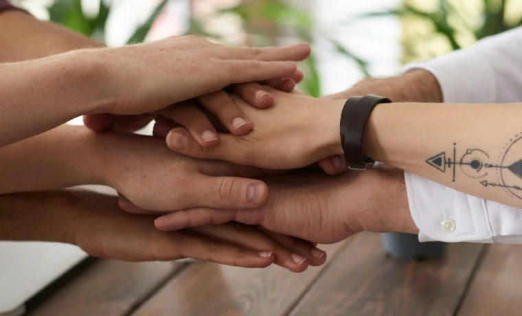 Multiple hands joined together in shared commitment and trust